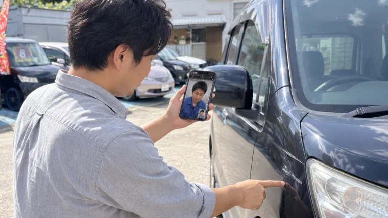 お客さんが車の横でスマホを持ち、LINEのビデオ通話で車の気になる場所を映している場面
